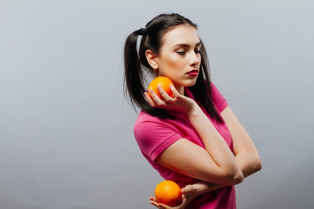 mujer poensativa con dos naranjas en las manos