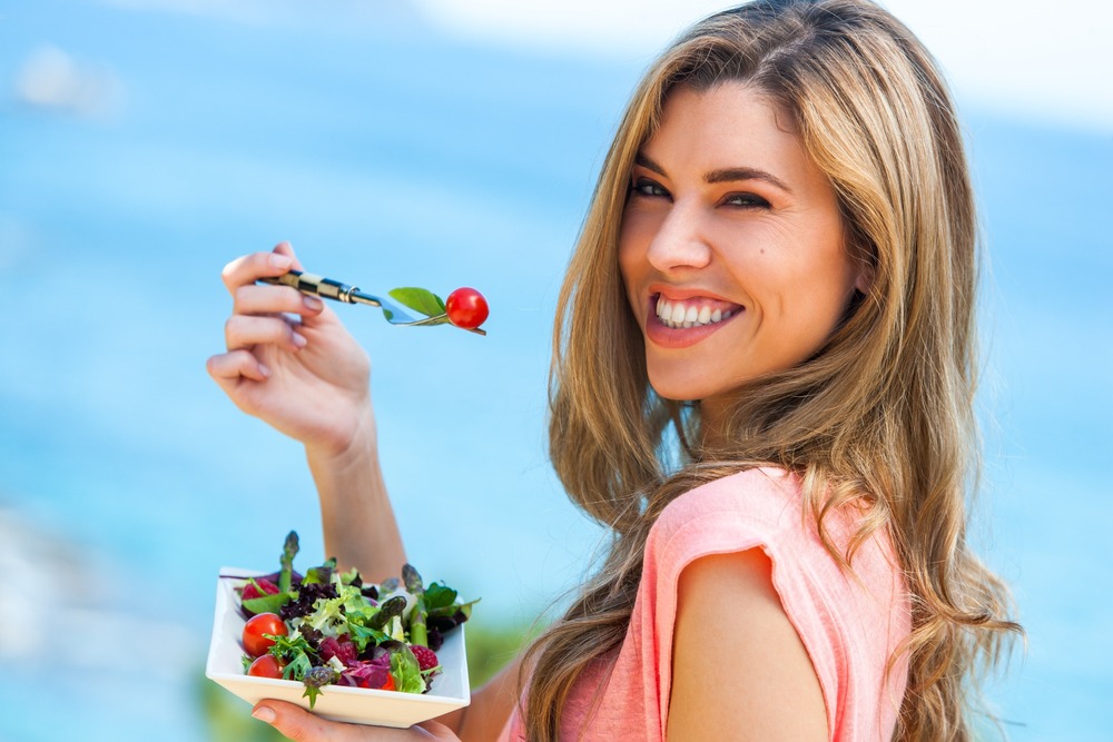 mujer ssonriente comiendo ensalada